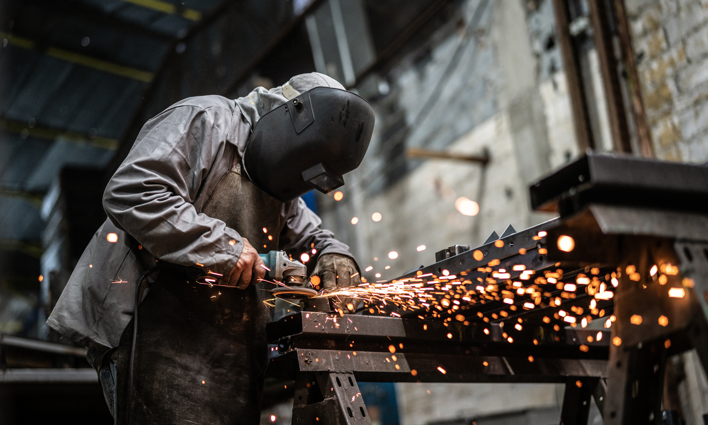 Worker welding metal with sparks in an industrial setting