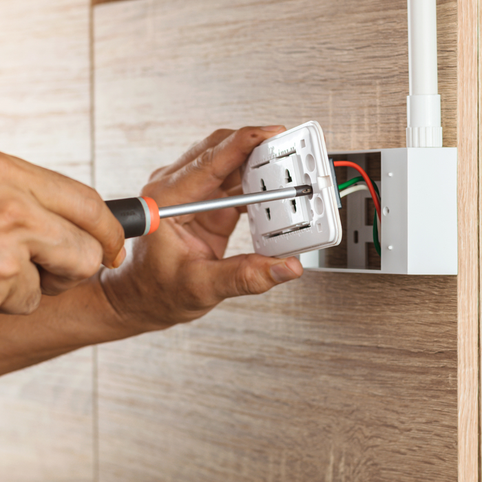 Person installing an electrical outlet with a screwdriver.