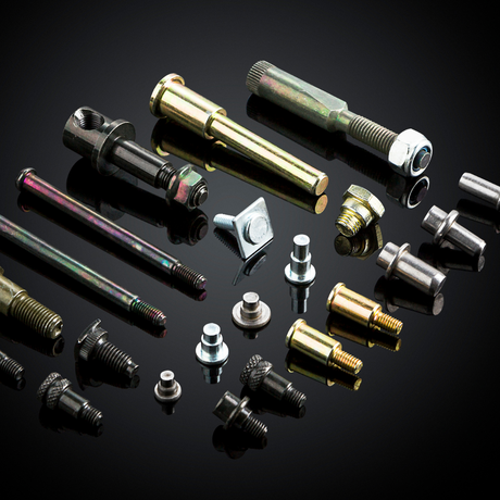 Collection of various metal bolts and screws on a reflective black surface