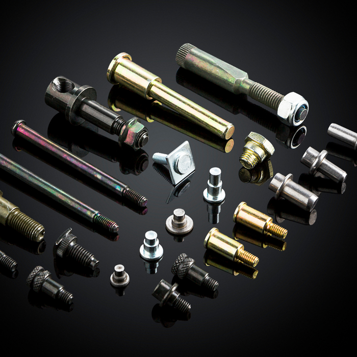 Collection of various metal bolts and screws on a reflective black surface