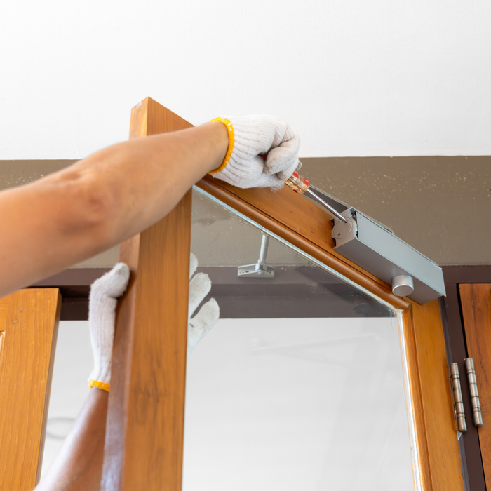 Person installing a wooden window frame with a tool.